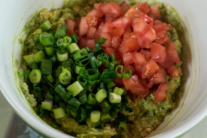 picture of mashed avocado topped with diced tomato and sliced green onion