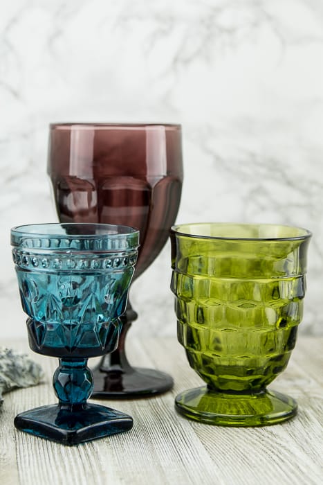 picture showing three pressed glass goblets in blue, green and purple, various heights and patterns