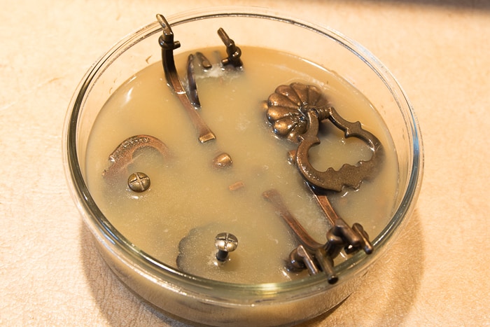 picture of brass hardware soaking in lemon juice in round glass bowl