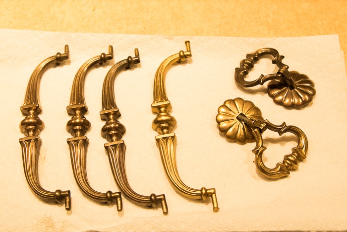 picture of brass hardware with two pieces fully restored to shiny gold finish