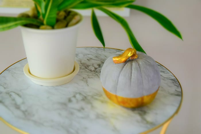 picture of round marble and gold table top with plant and concrete gold dipped pumpkin