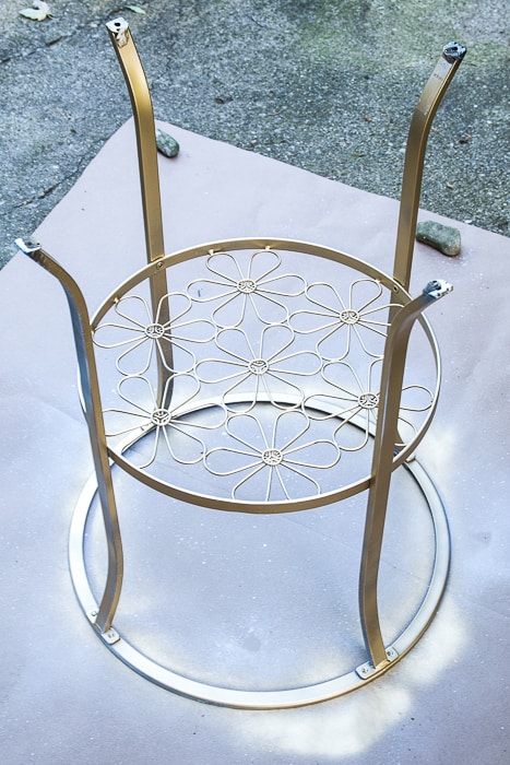 picture of primed and gold spray painted round metal table upside down outside
