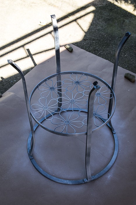 picture of black metal table upside down with primer coat sprayed on