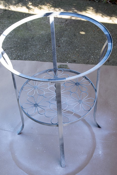 Picture of upright round metal table with primer coat sprayed on