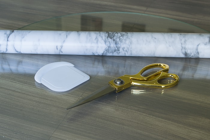 picture of marble shelf liner paper, gold scissors and plastic dough scraper