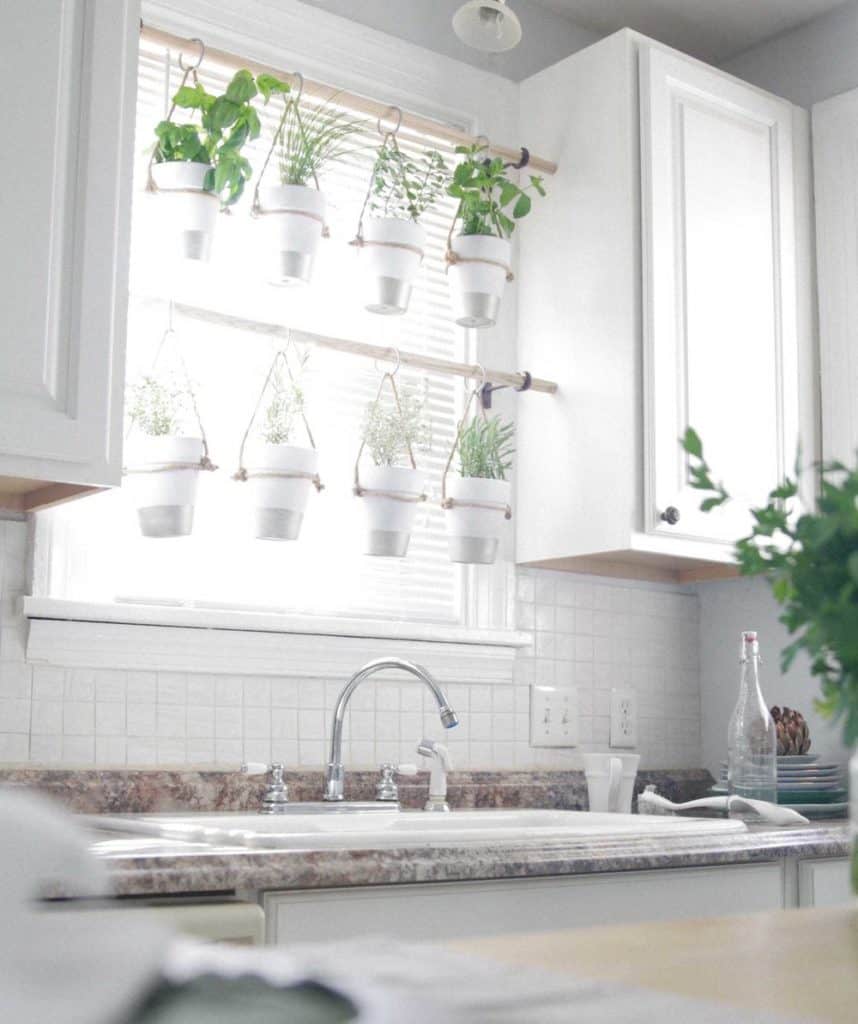 picture of herb pots hanging from rods in a kitchen window