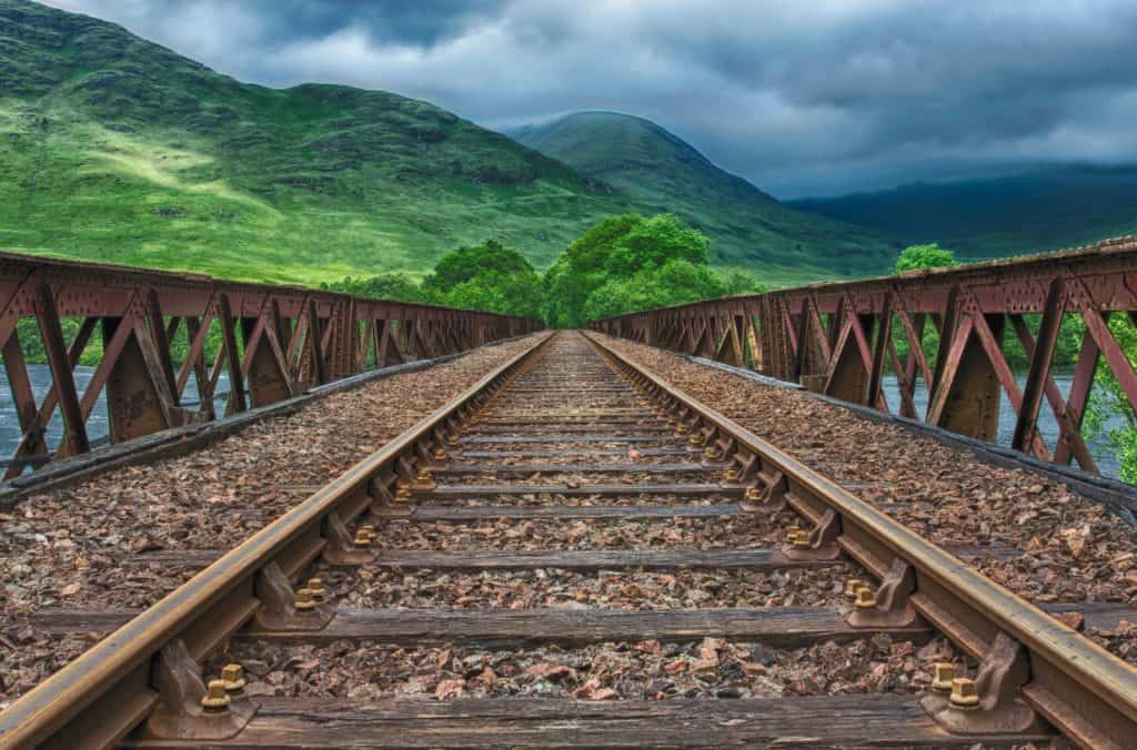 railroad tracks leading to beautiful green mountains