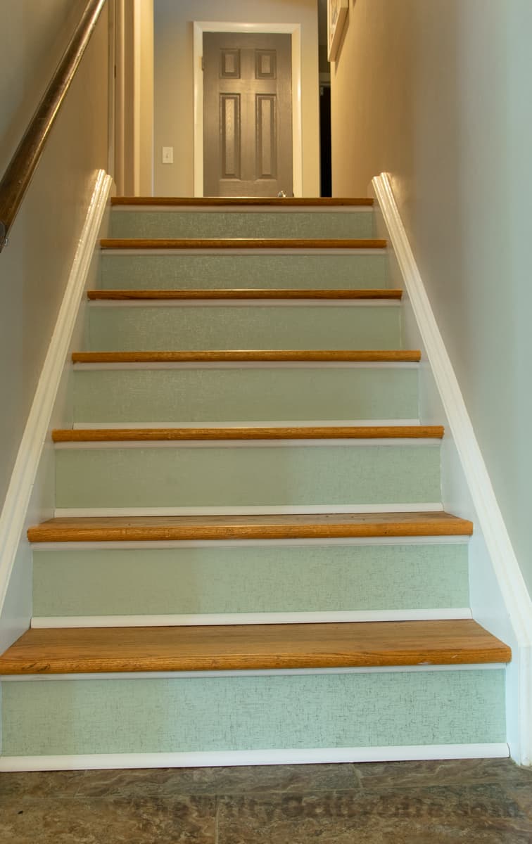 nearly finished stairs with temporary wallpaper attached and trim cut and painted