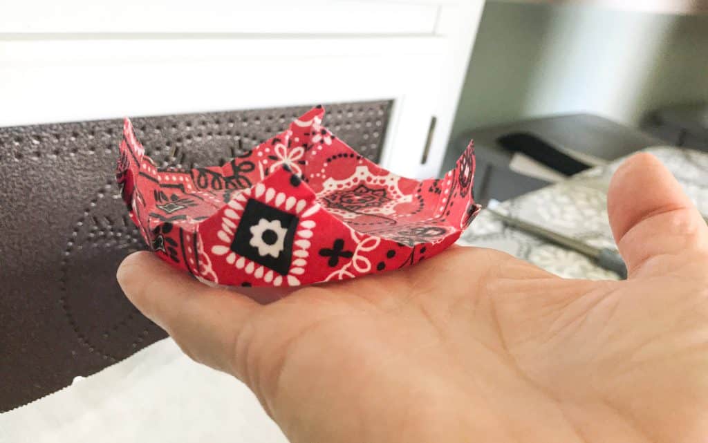 Hand holding wax bowl cover upside down to demonstrate how fabric stays in place after it is removed from the bowl