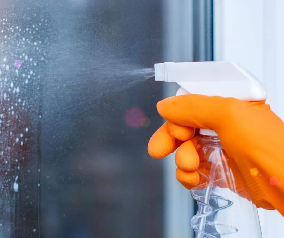 bottle spraying cleaner onto glass