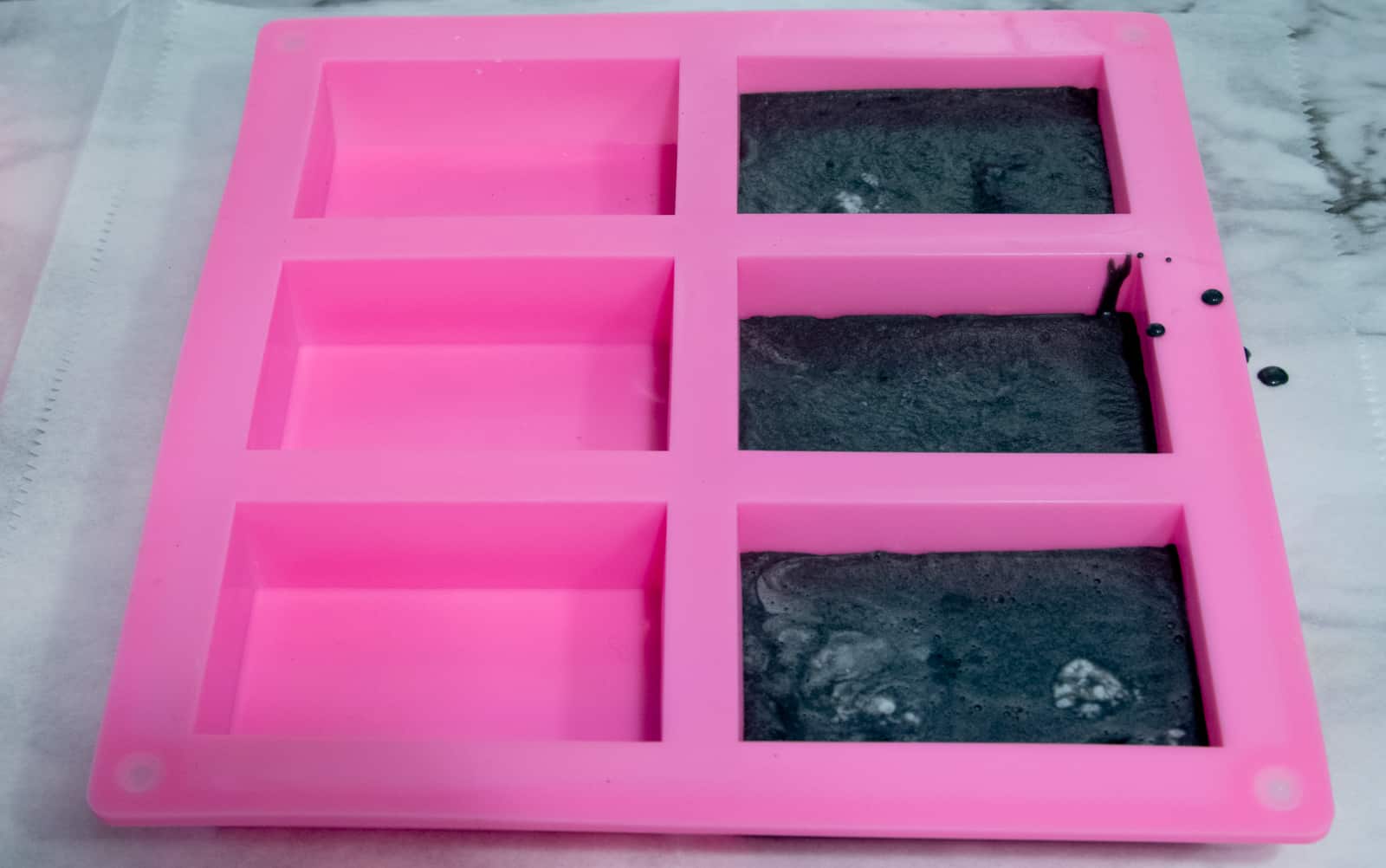 silicone molds partially filled with activated charcoal soap mixture