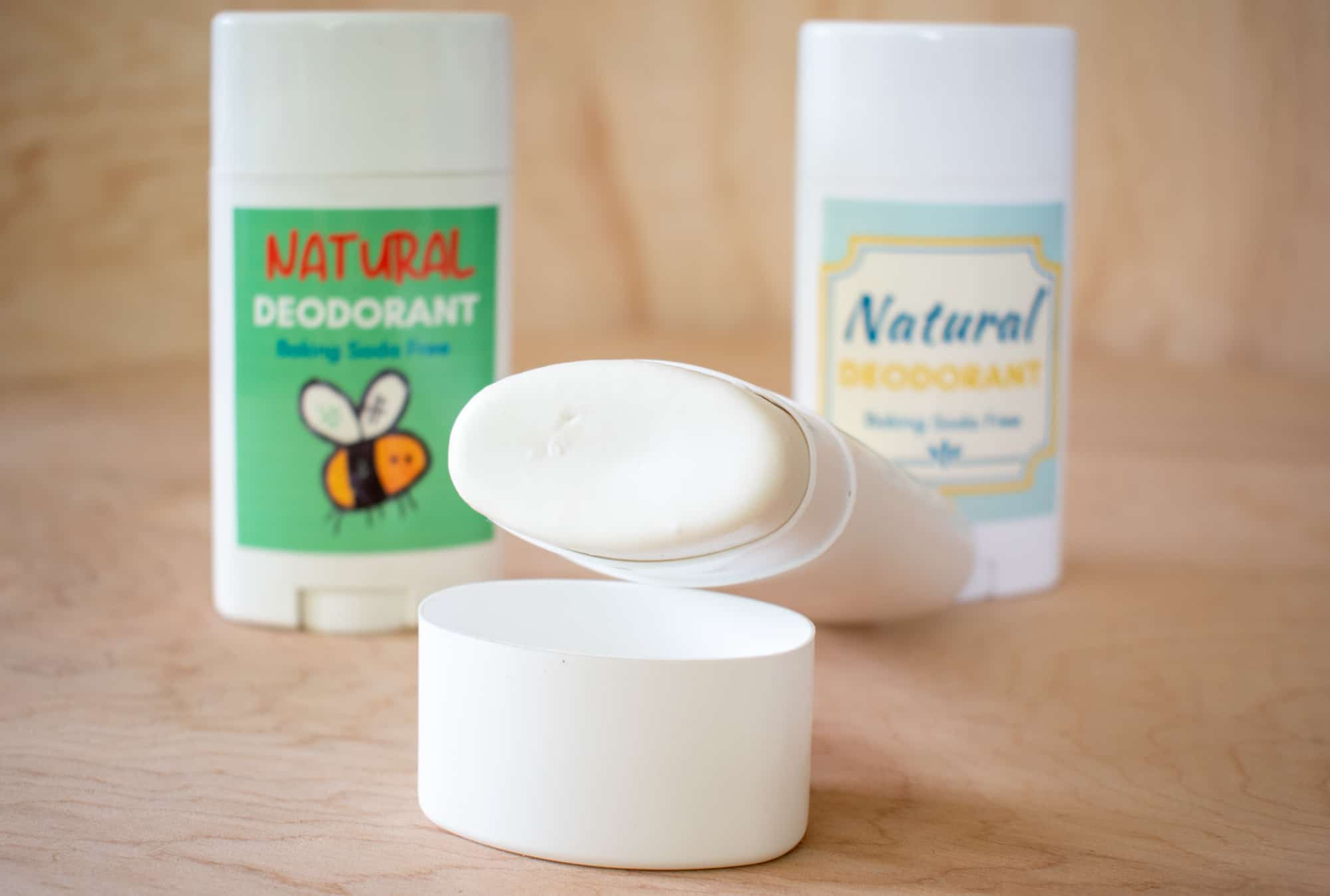 image of three sticks of all natural baking soda free deodorant, one on its side with cap off to show contents