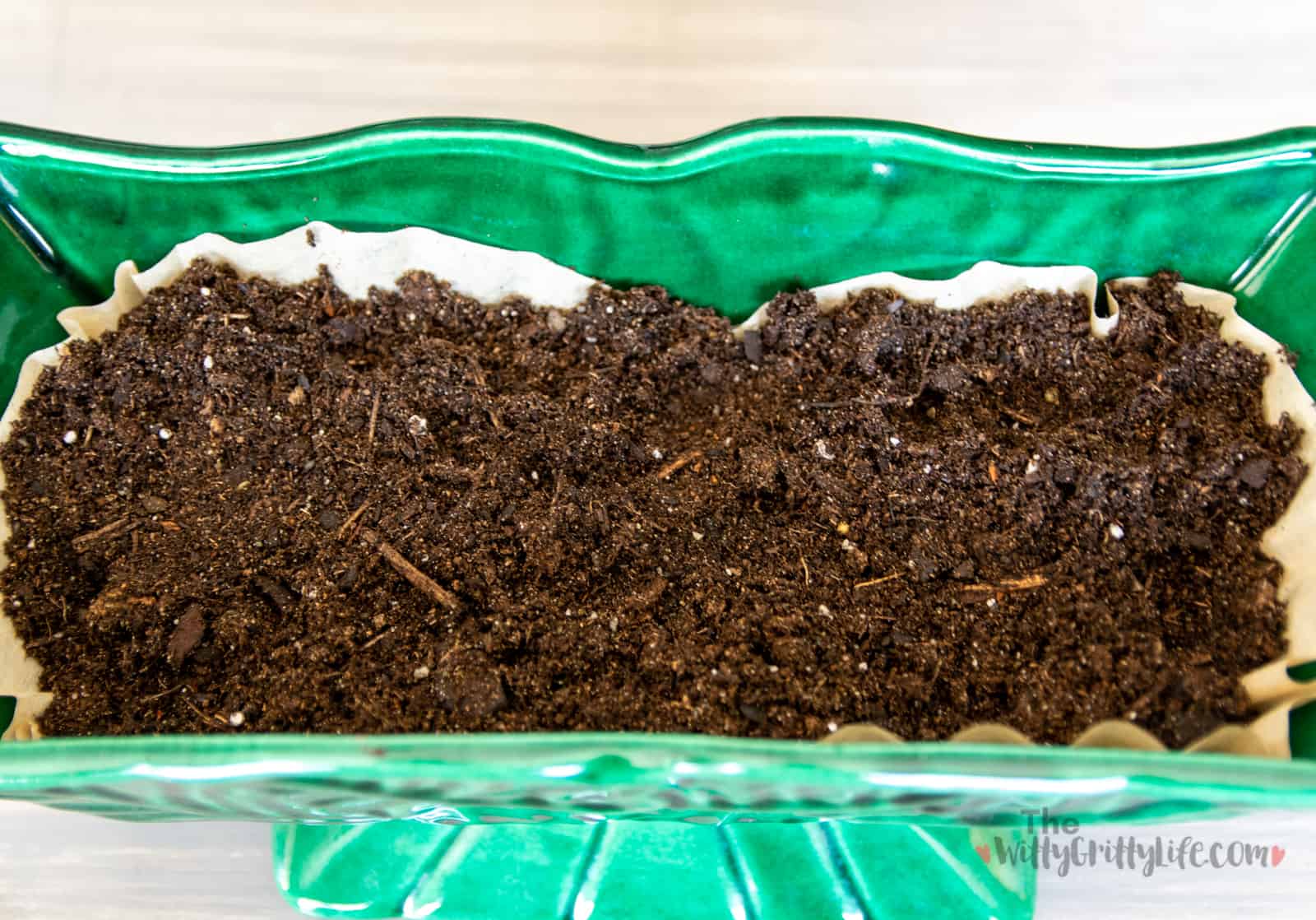 planter with potting soil on top of drainage pebbles and coffee filters