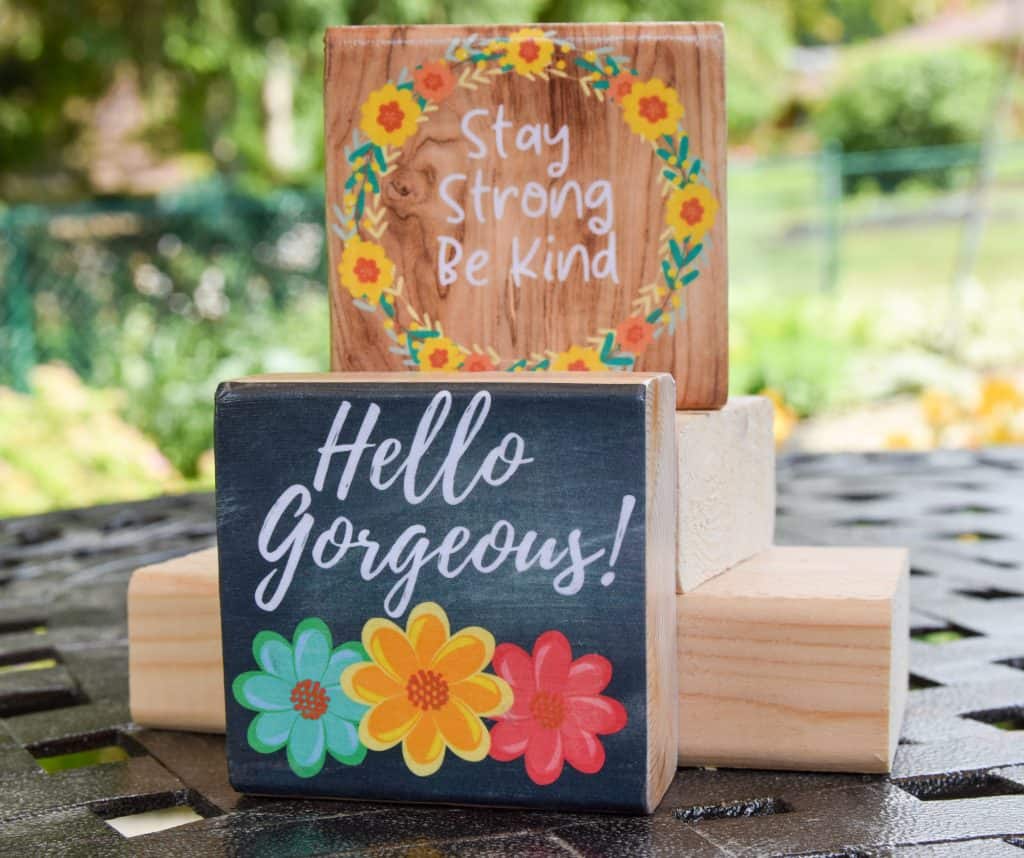 image with wooden blocks one with chalkboard background and flowers stating: hello gorgeous the other featuring a flower wreath and quote: stay strong be kind